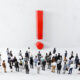 Group of business people looking at large red exclamation mark symbol on wall Group of business people looking at large red exclamation mark symbol on wall.