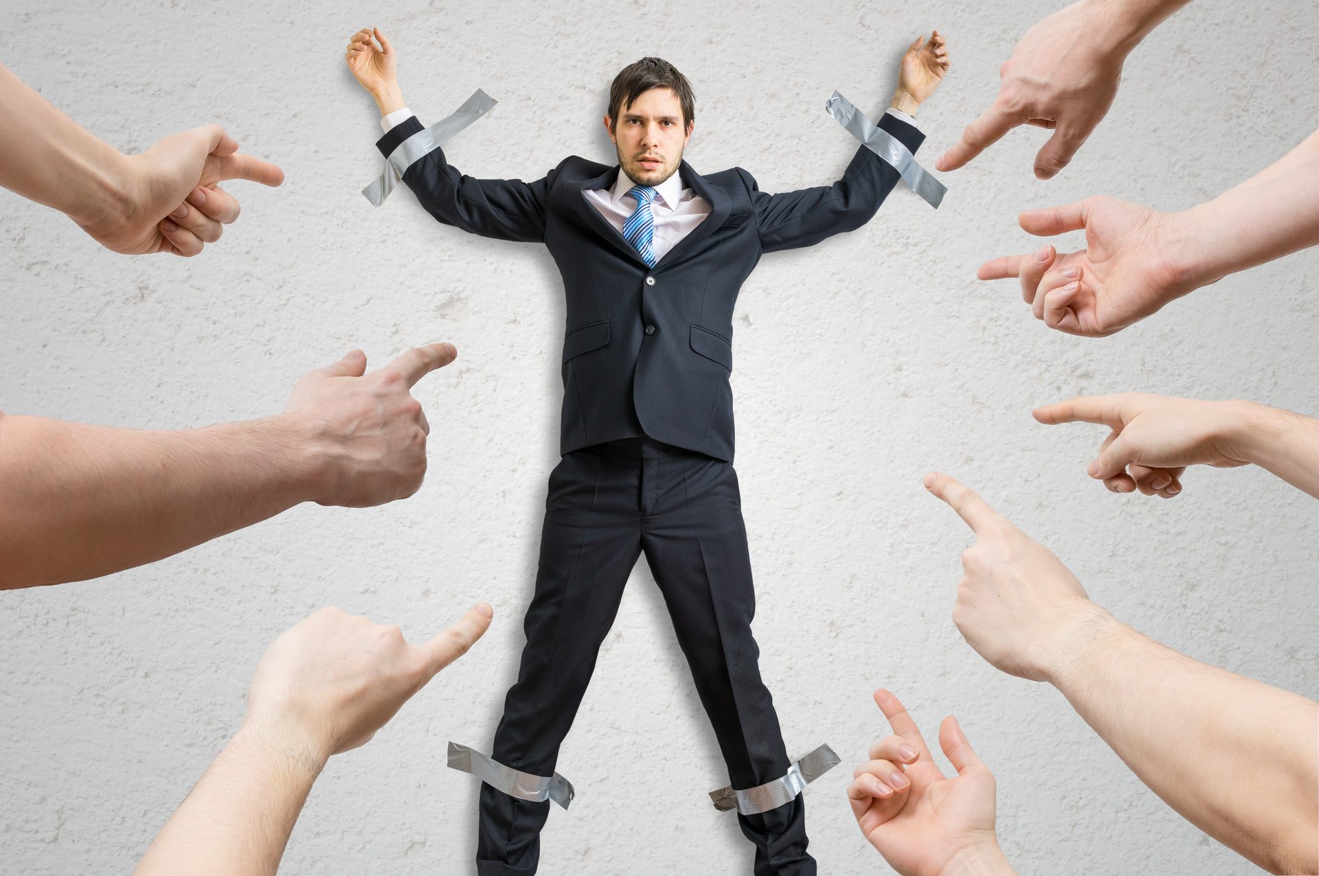 Many hands blame employee who is taped to the wall.
